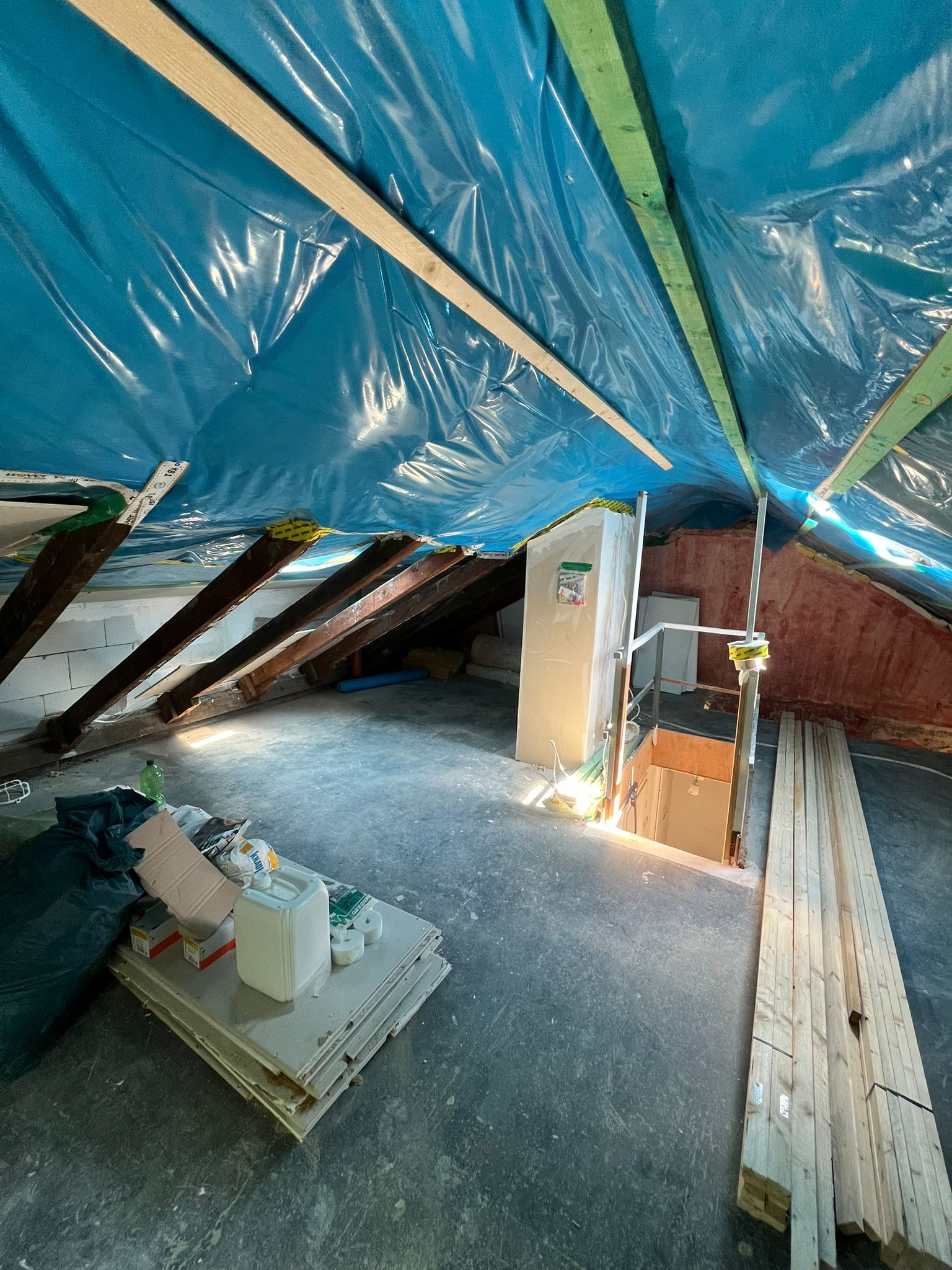 Dachgeschoss vor dem Ausbau mit sichtbarer Dampfsperrfolie und Dachbalken
