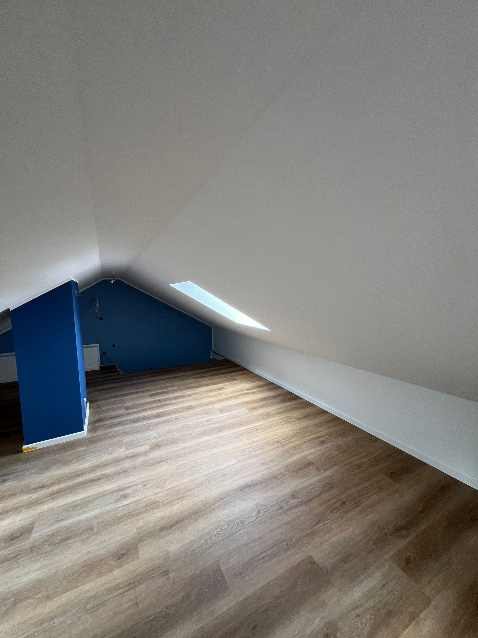 Modernisierter Dachgeschoss-Wohnraum mit Holzfußboden und schrägen Decken